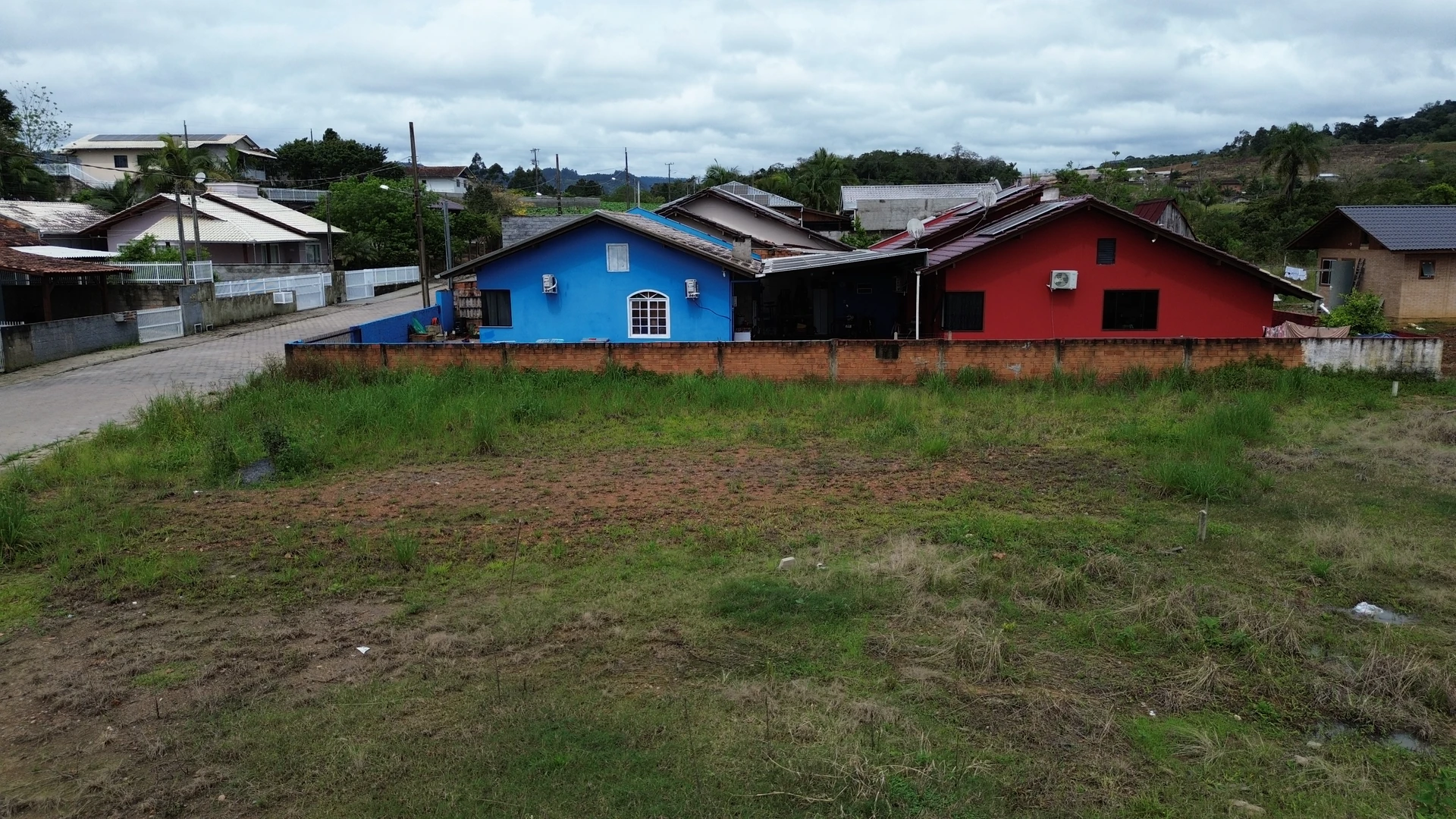 Vista lateral do terreno de 360 m², com imóveis vizinhos ao fundo
